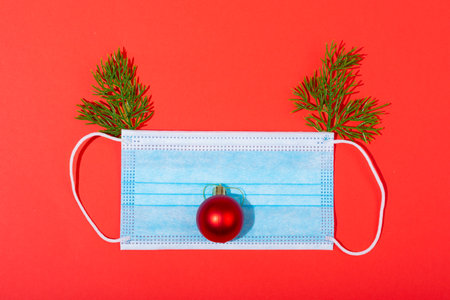 Composition of face mask with christmas decorations in shape of reindeer on green background. christmas, tradition and celebration during coronavirus pandemic concept.の写真素材