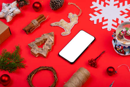 Composition of smartphone with copy space and christmas decorations on red background. christmas,...