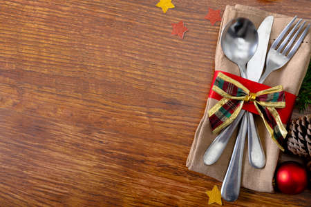 Composition of christmas decorations with cutlery and copy space on wooden background. christmas, tradition and celebration concept.の写真素材