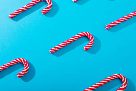 Composition of multiple rows of candy canes on blue background. christmas, tradition and celebration...