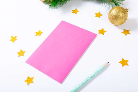 Composition of pink card with copy space, stars, pencil and bauble on white background. christmas, tradition and celebration concept.の写真素材