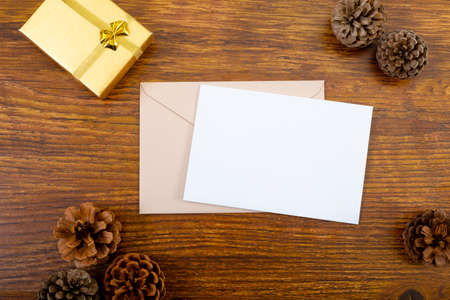 Composition of white card with copy space, envelope and pine cones on wooden background. christmas, communication, tradition and celebration concept.の写真素材