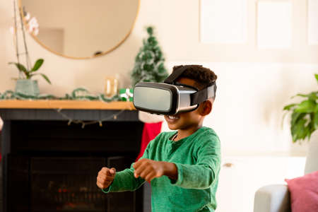 African american boy wearing vr headset and having fun at christmas time. childhood, leisure and...