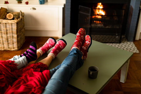 Feet of caucasian family wearing christmas socks and sitting on sofa at christmas time. family christmas time and festivity together at home.の写真素材