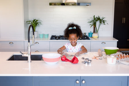 Happy african american messy girl baking in kitchen. baking and cooking, childhood and leisure time...