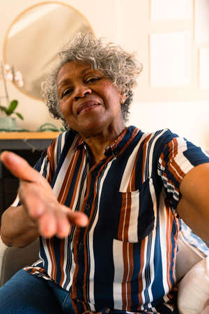 Smiling african american senior woman sitting in armchair and gesturing. healthy retirement...