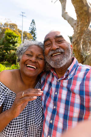 Happy african american senior couple taking selfie and hugging. active retirement lifestyle at home...