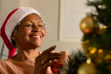 Happy african american senior woman decorating christmas tree. christmas, festivity and tradition at home. festivity together at home.の写真素材