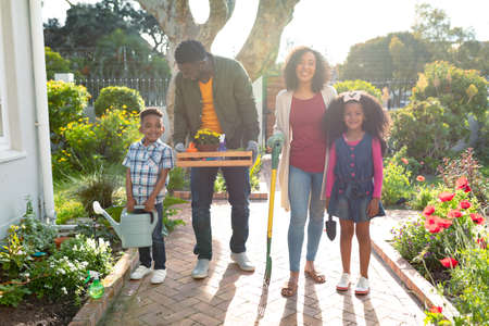 Happy african american family standing with garden tools and looking at camera. family time, having...