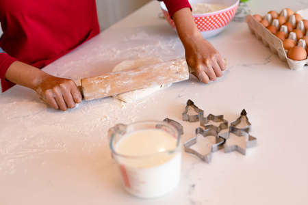 Hands of african american woman wearing apron, rolling dough for baking. cooking and baking,...
