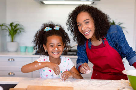 Happy african american mother and daughter baking together in kitchen. family time, having fun...
