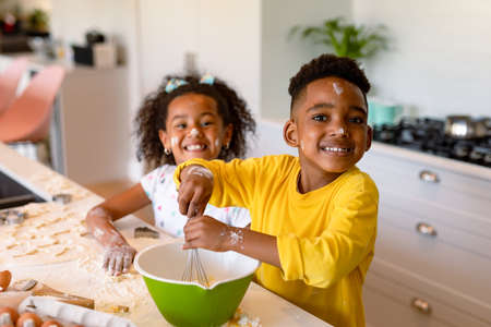 Happy african american siblings baking in kitchen. baking and cooking, childhood and leisure time at home.の写真素材