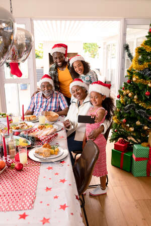 Happy multi generation family wearing santa hats, taking selfie. family christmas time and festivity together at home.の写真素材