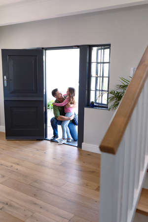 Happy caucasian siblings welcoming father returning home after work. family time, having fun together at home.の写真素材