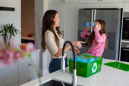 Happy caucasian mother and daughter segregating rubbish. recycling, waste selection, spending time together at home.の写真素材