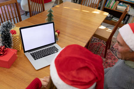 Caucasian woman and senior man having video call on laptop with copy space at christmas time. christmas, festivity and communication technology at home.の写真素材