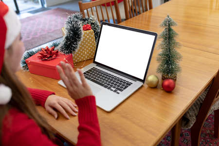 Caucasian woman wearing santa hat having video call on laptop with copy space at christmas time....
