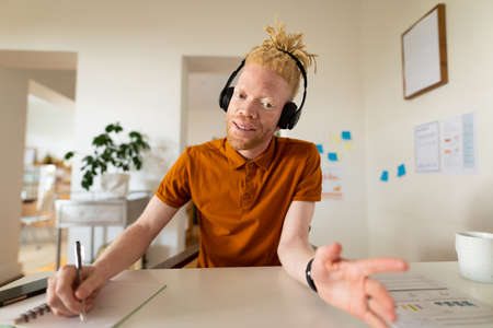 Albino african american man working from home making video call. remote working using technology at home.の写真素材