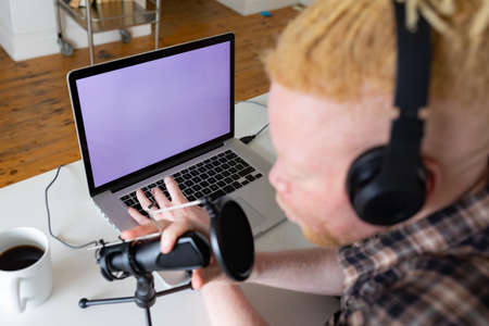 Happy albino african american man with dreadlocks working from home and making podcast. remote working using technology at home.の写真素材