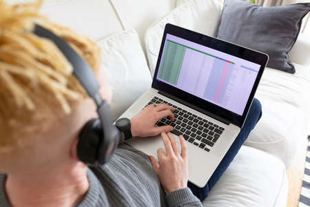 Albino african american man in the living room using laptop. leisure time using technology, relaxing...