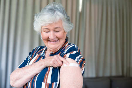 Happy senior caucasian woman showing plaster after vaccination. senior health and lifestyle during  pandemic.の写真素材