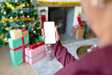 Caucasian woman using smartphone with copy space at christmas time. christmas, festivity and communication technology.の写真素材