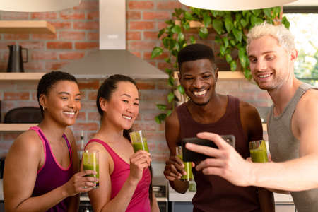 Group of diverse female and male friends preparing smoothie together and taking selfie. fitness and healthy, active lifestyle.の写真素材