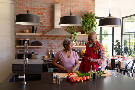 Happy african american senior couple cooking together in kitchen. retirement lifestyle, leisure and spending time at home.の写真素材