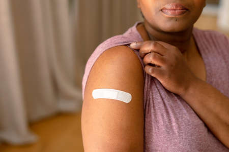African american senior woman showing plaster after vaccination. senior health and lifestyle during...