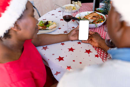 Hands of fafrican american senior couple using smartphone with copy space at christmas time. retirement lifestyle, christmas festivities and communication technology.の写真素材