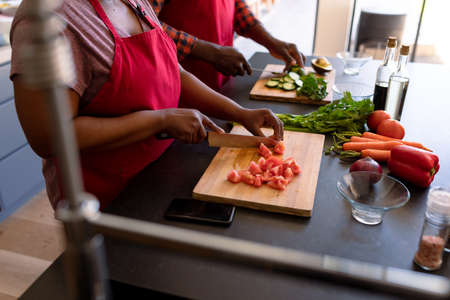 Midsection of african american senior couple cooking together in kitchen. retirement lifestyle,...
