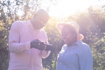 Happy african american senior couple taking selfie outdoors. retirement lifestyle, spending time at home and garden.の写真素材