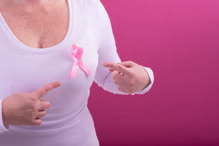 Midsection of caucasian woman in white tshirt with pink ribbon gesturing. breast cancer positive awareness campaign concept digitally generated video.の写真素材