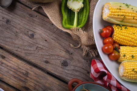 Composition of autumn halloween corn, tomatoes and pepper with copy space on wooden background....