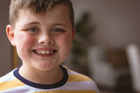 Close up portrait of caucasian boy smiling standing in the living room at home. childhood and home conceptの写真素材