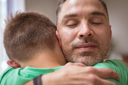 Close up view of caucasian father hugging his son at home. fatherhood and love conceptの写真素材