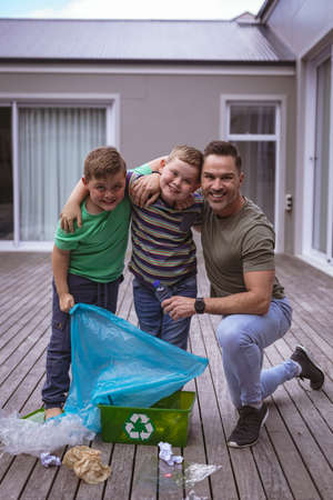 Portrait of caucasian father and two sons collecting plastic materials in a bag outdoors. plastic recycling and pollution control conceptの写真素材