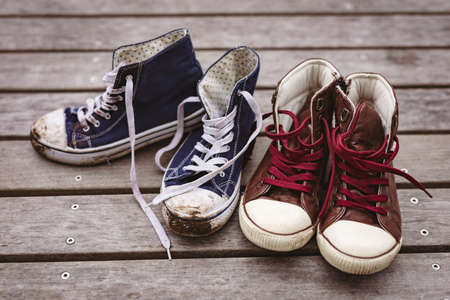 High angle close-up of dirty blue canvas by red pair of new shoes on floorboard. fashion and contrastsの写真素材