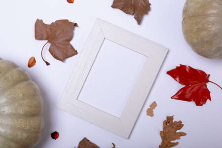 Pumpkin, autumn leaves and empty frame with copy space on white surface. autumn season and halloween conceptの写真素材