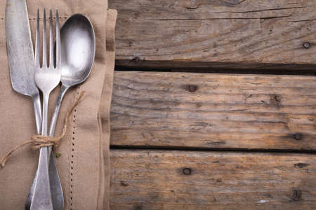 Close up of cutlery set over a napkin on wooden surface. autumn season and restaurant concept