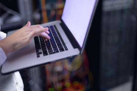 Mid section of woman laptop in computer server room. database server management and maintenance...