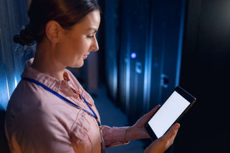 Caucasian female engineer using digital tablet with copy space in computer server room. database server management and maintenance conceptの写真素材