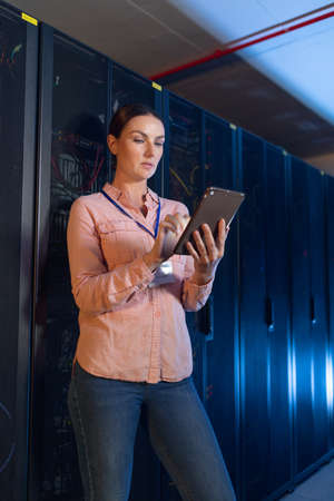 Caucasian female engineer using digital tablet in computer server room. database server management...