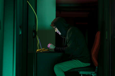 Asian male hacker using a laptop in computer server room. cyber crime and hacking conceptの写真素材