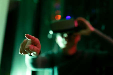 Asian man wearing vr headset touching an invisible screen in computer server room. database server and futuristic technology conceptの写真素材