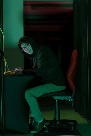 Asian male hacker using a laptop in computer server room. cyber crime and hacking conceptの写真素材
