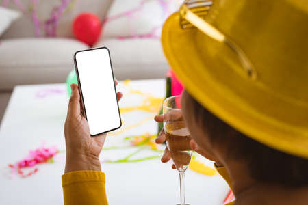 Elderly woman video calling through smart phone and enjoying champagne in party at home, copy space....