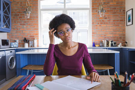 Portrait of tensed african american teenage girl studying at home. education, e-learning and online concept.の写真素材