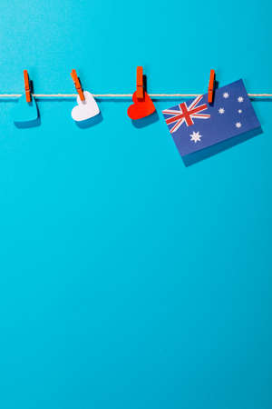 Australia flag and heart shapes hanging on clothesline with copy space against blue background. patriotism, symbol and identity.の写真素材