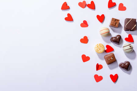 Chocolates with red heart shapes by copy space on white background. love and valentine sweets.の写真素材